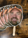 Cardboard cutout of a smiling person with sunglasses on a wooden surface